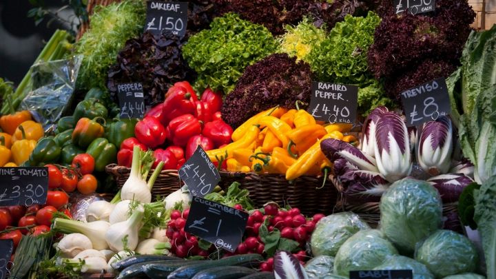 Dettaglio di un banco con verdura assortita al supermercato tra cui peperoni, zucchine, ravanelli