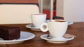 Due caffè e una fetta di torta Sacher sul tavolino di un bar