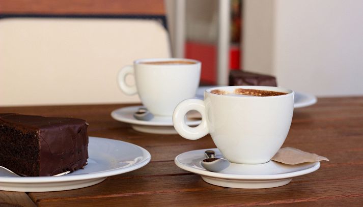 Due caffè e una fetta di torta Sacher sul tavolino di un bar
