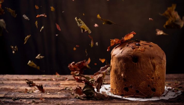 Panettone ad ottobre su un tavolo in legno con foglie secche che cadono