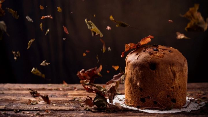 Panettone ad ottobre su un tavolo in legno con foglie secche che cadono