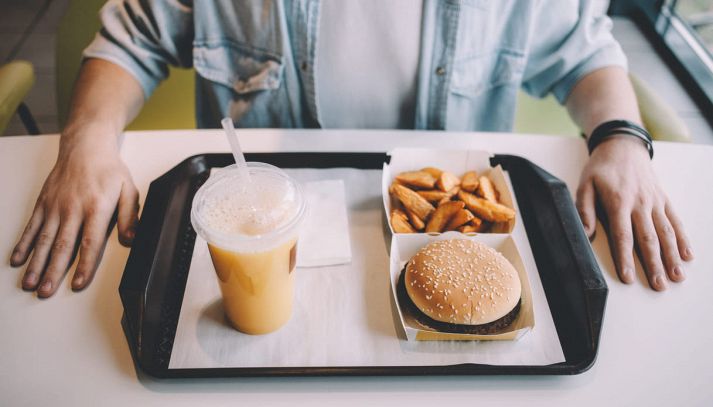 Uomo al fast food che mangia un menu classico