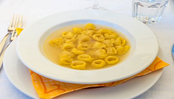 Tavolo con piatto di tortellini in brodo