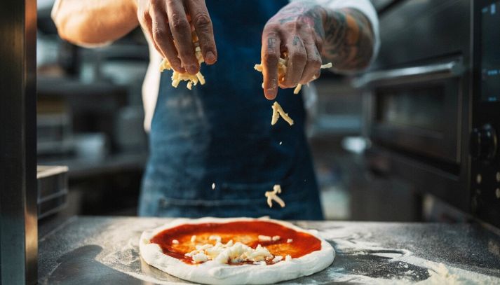 Cucina del ristorante con pizzaiolo in primo piano che lavora