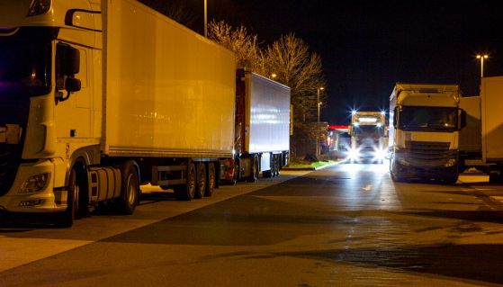 Dei camion in movimento o a parcheggiati a bordo strada presidiano un tratto di strada di sera per uno sciopero 
