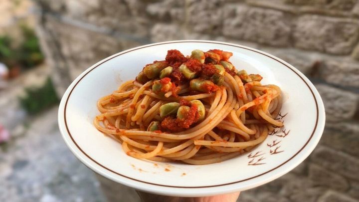 Piatto con spaghetti alla puttanesca di fave su sfondo sfumato