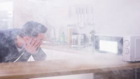 Microonde da cui esce fumo e uomo che guarda