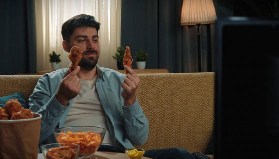 Uomo sul divano che mangia cibo spazzatura