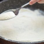 Pentola con il latte e mano che versa semolino