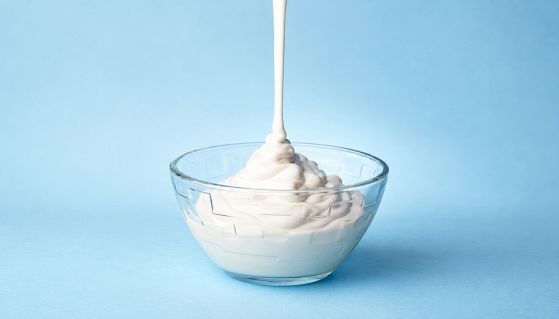 Yogurt bianco elastico che cola in una coppetta di vetro