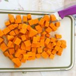 Zucca a cubetti sul tagliere con il coltello