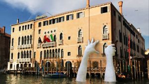 Biennale di Venezia: mani giganti emergono dal Canal Grande