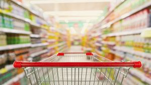 Supermarket aisle interior blur background with empty red shopping cart
