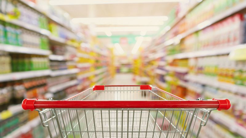 Supermarket aisle interior blur background with empty red shopping cart