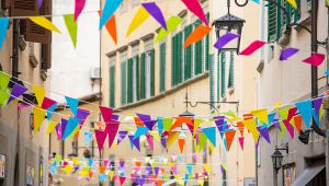 Bandiere triangolari colorate appese tra i palazzi decorano una stretta via di centro storico per una festa all’aperto