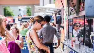 Persone in fila davanti a un colorato food truck all’aperto durante una festa di strada affollata