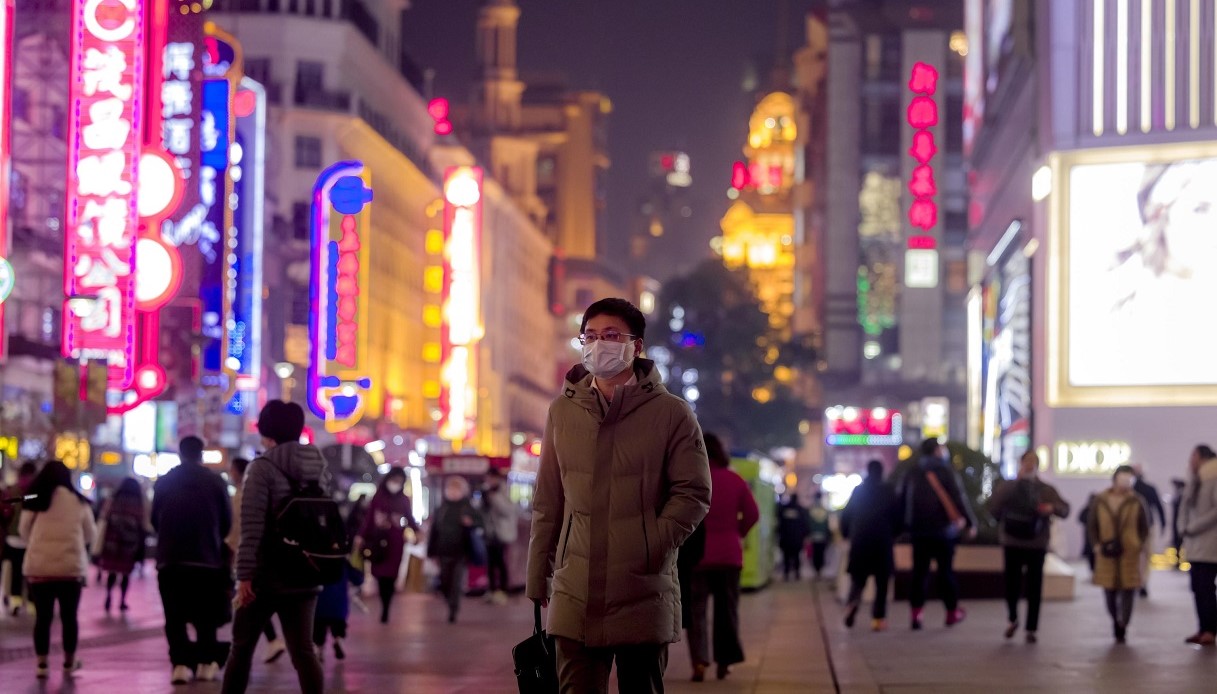 Un uomo cammina nel distretto dello shopping di Shanghai. 