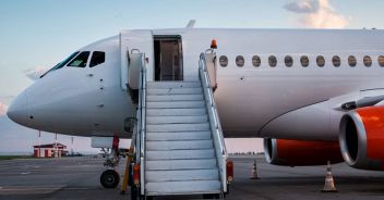 Modern passenger airplane with boarding stairs at the airport apron