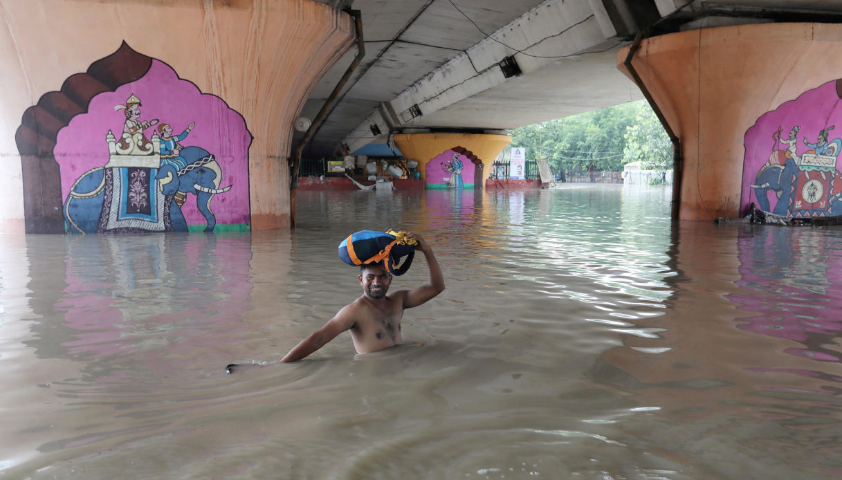 Un uomo attraversa un'area allagata sotto un ponte a Nuova Delhi in India