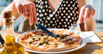 woman eating pizza in cafe