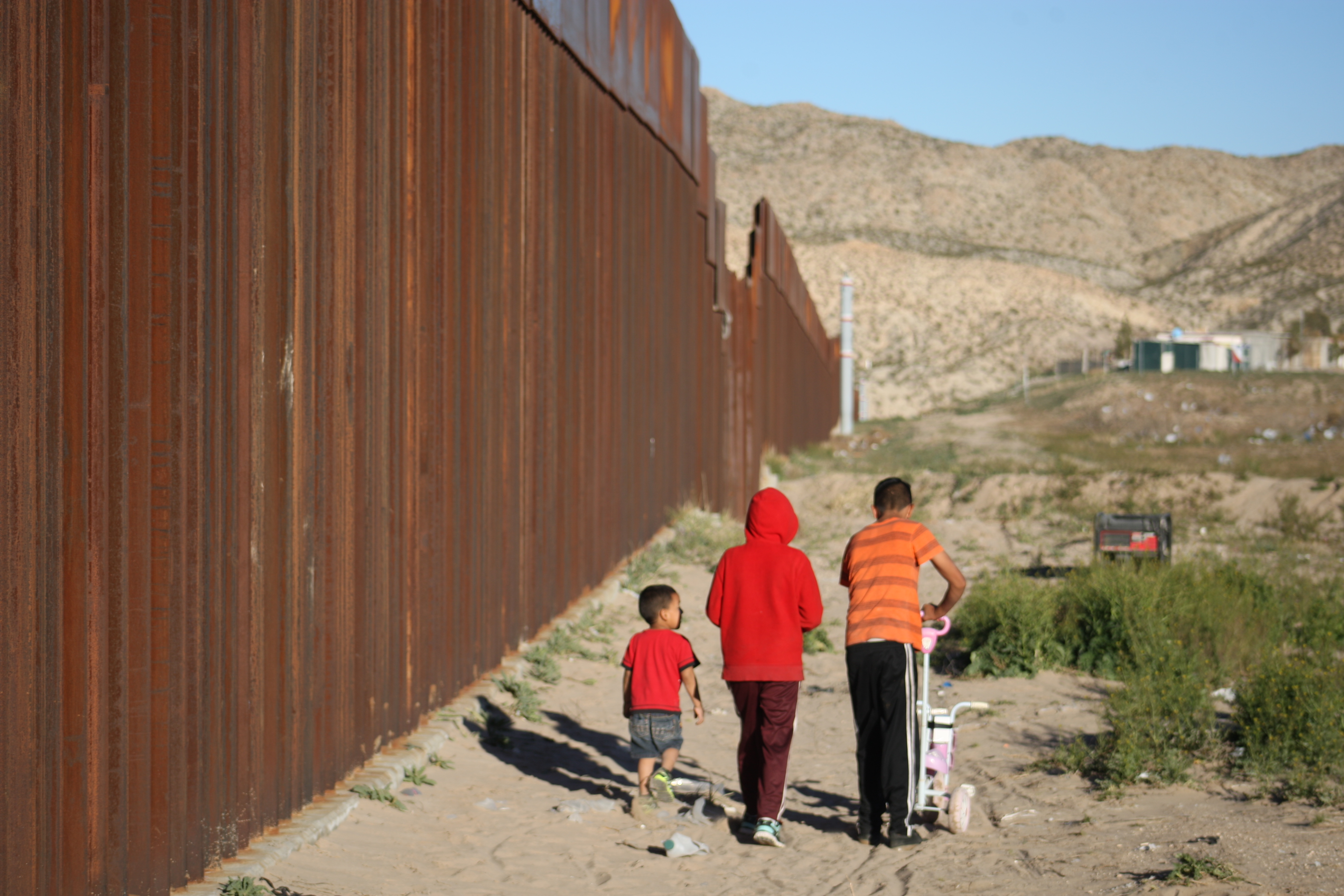 Bambini messicani camminano lungo il muro Usa-Messico