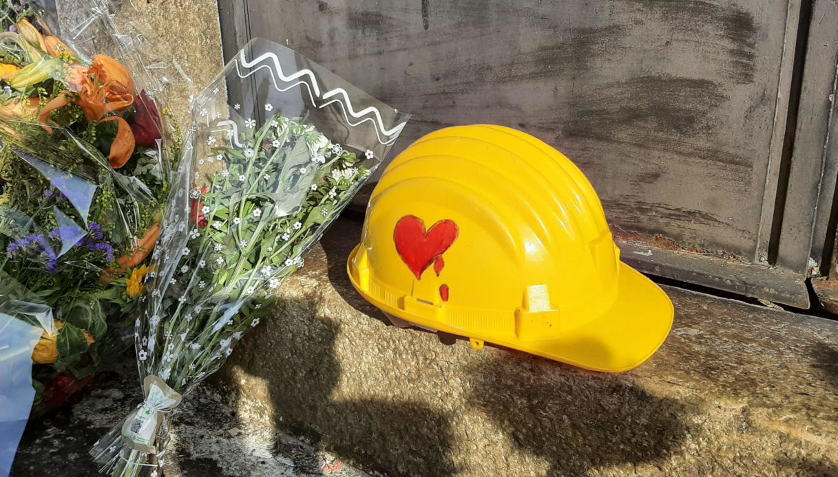 Mazzi di fori e un casco di protezione giallo, con disegnato su un lato un cuore rosso che sanguina, su di uno scalino di una porta d'ingresso della stazione di Brandizzo, nel Torinese, dove cinque operai sono morti travolti da un treno