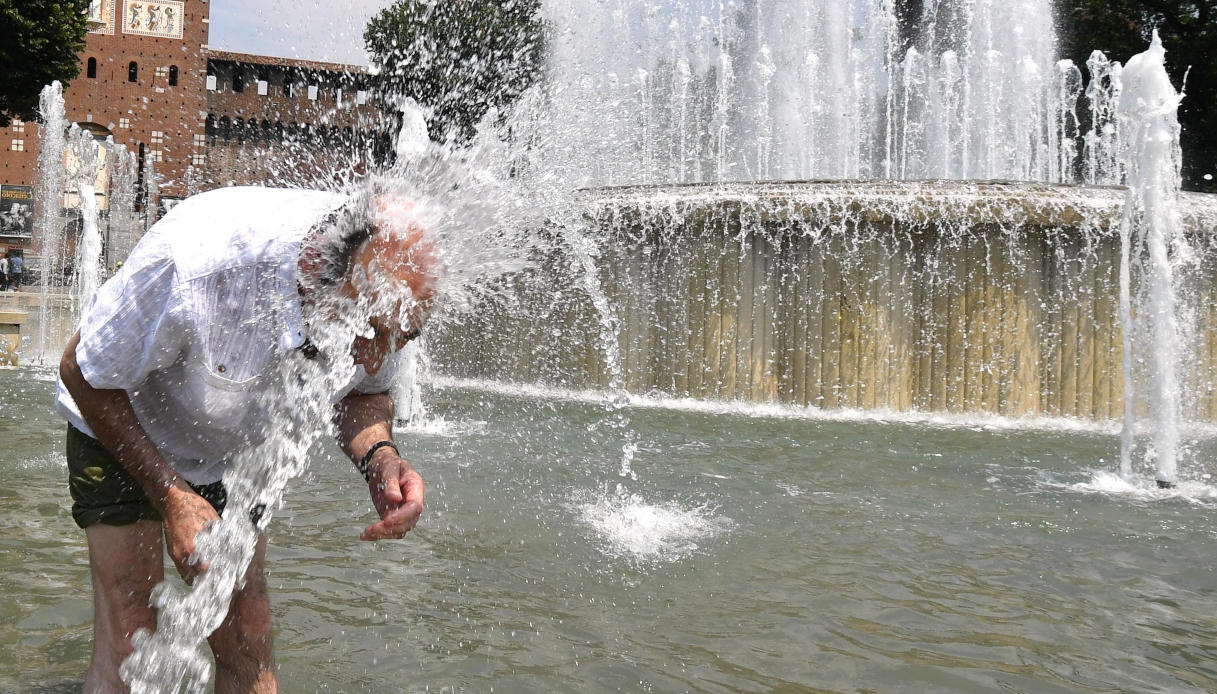 Un uomo si difende dalle alte temperature cercando refrigerio nella fontana di piazza del Castello, a Milano