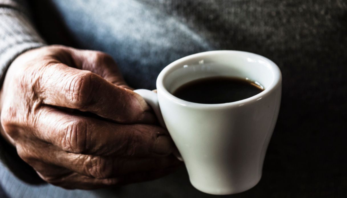 Persona anziana con una tazza di caffè in mano