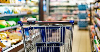 A shopping cart by a store shelf in a supermarket