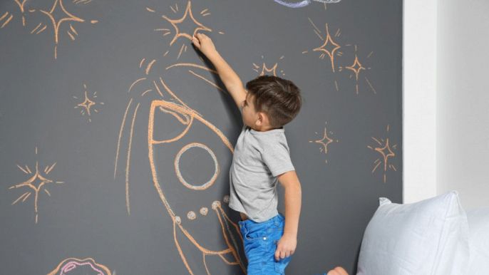 bambino che disegna su una parete con pittura lavagna