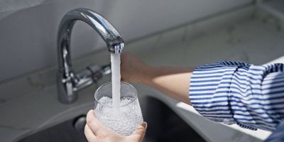 persona che riempie di acqua dal rubinetto di casa