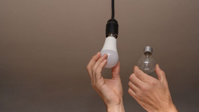 una persona sostituisce la vecchia lampada alogena con una a led