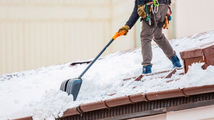 uomo pulisce ed elimina la neve dal tetto