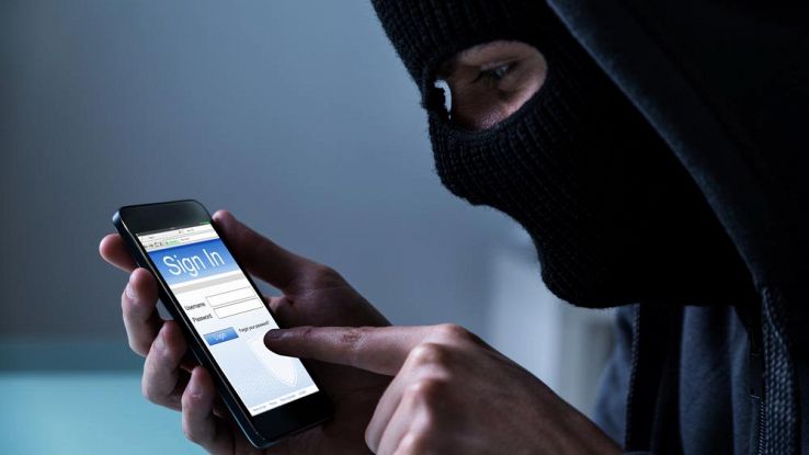 Un uomo incappucciato usa uno smartphone