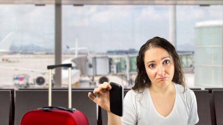 Donna triste in aeroporto con telefono in mano