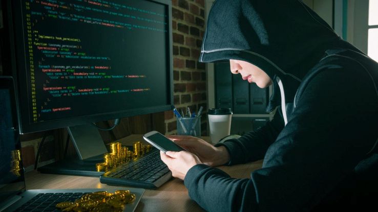 Un hacker incappucciato usa uno smartphone