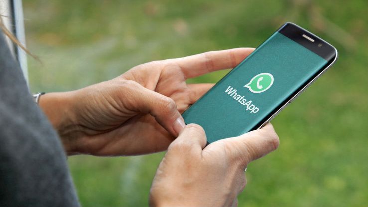 Una persona usa a due mani uno smartphone che ha l'icona di WhatsApp a tutto schermo