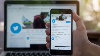 Uno smartphone in primo piano aperto sul social Twitter e uno PC sullo sfondo sempre collegato a Twitter