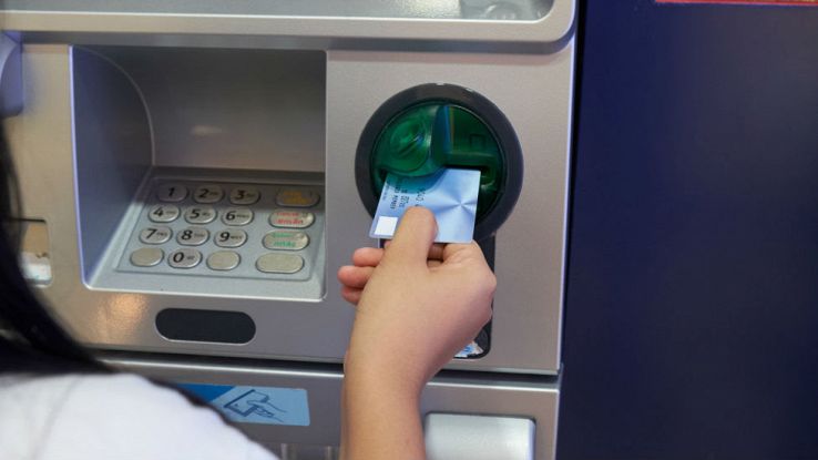 Una donna inserisce la propria carta di credito su uno sportello ATM