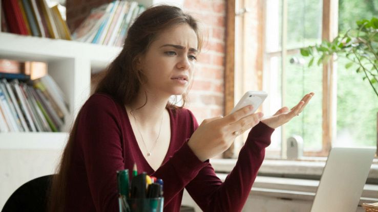 Una ragazza disperata mentre guarda il proprio telefono