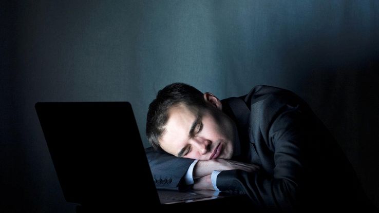 uomo che dorme davanti a pc acceso