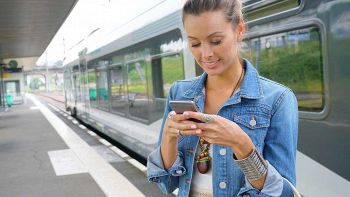 Ragazza con smartphone vicino al treno