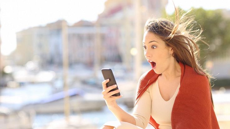 ragazza stupita che guarda lo schermo dello smartphone