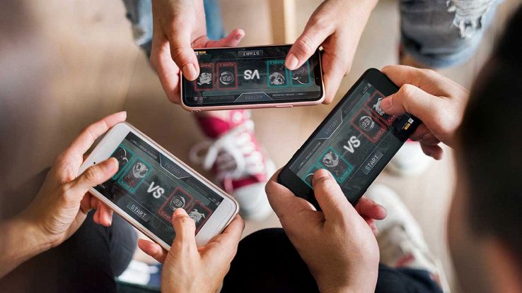 Tre ragazzi giocano con lo smartphone