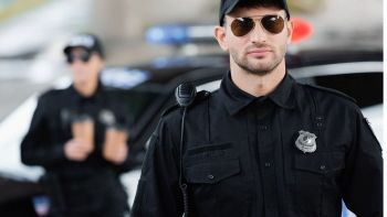 Poliziotto in primo piano in servizio che scruta attentamente il paesaggio.