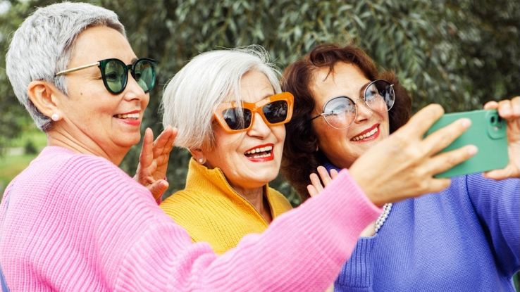 Tre signore di circa 60 anni si scattano una foto con lo smartphone da postare sui social