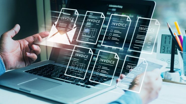 Un uomo di fronte a un laptop con molteplici fatture elettroniche