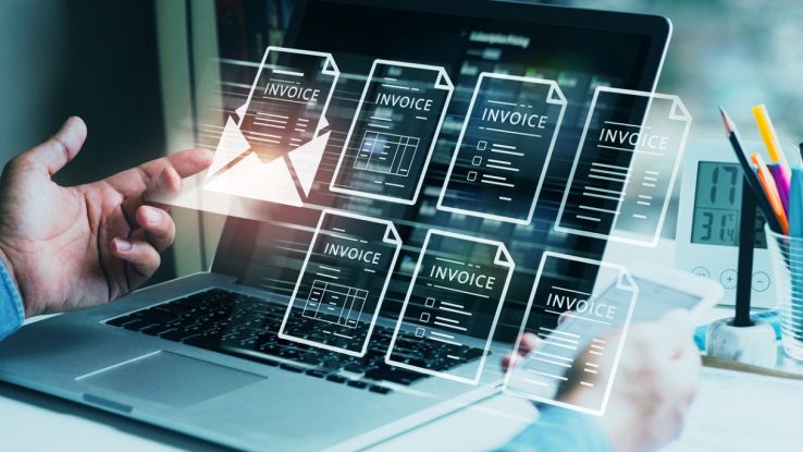 Un uomo di fronte a un PC con diverse fatture elettroniche aperte