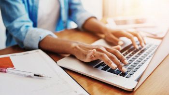 Una donna digita sulla tastiera di un portatile