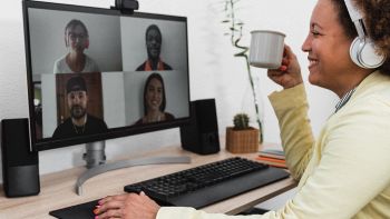 Persona in smart working che partecipa a una video call con webcam su monitor